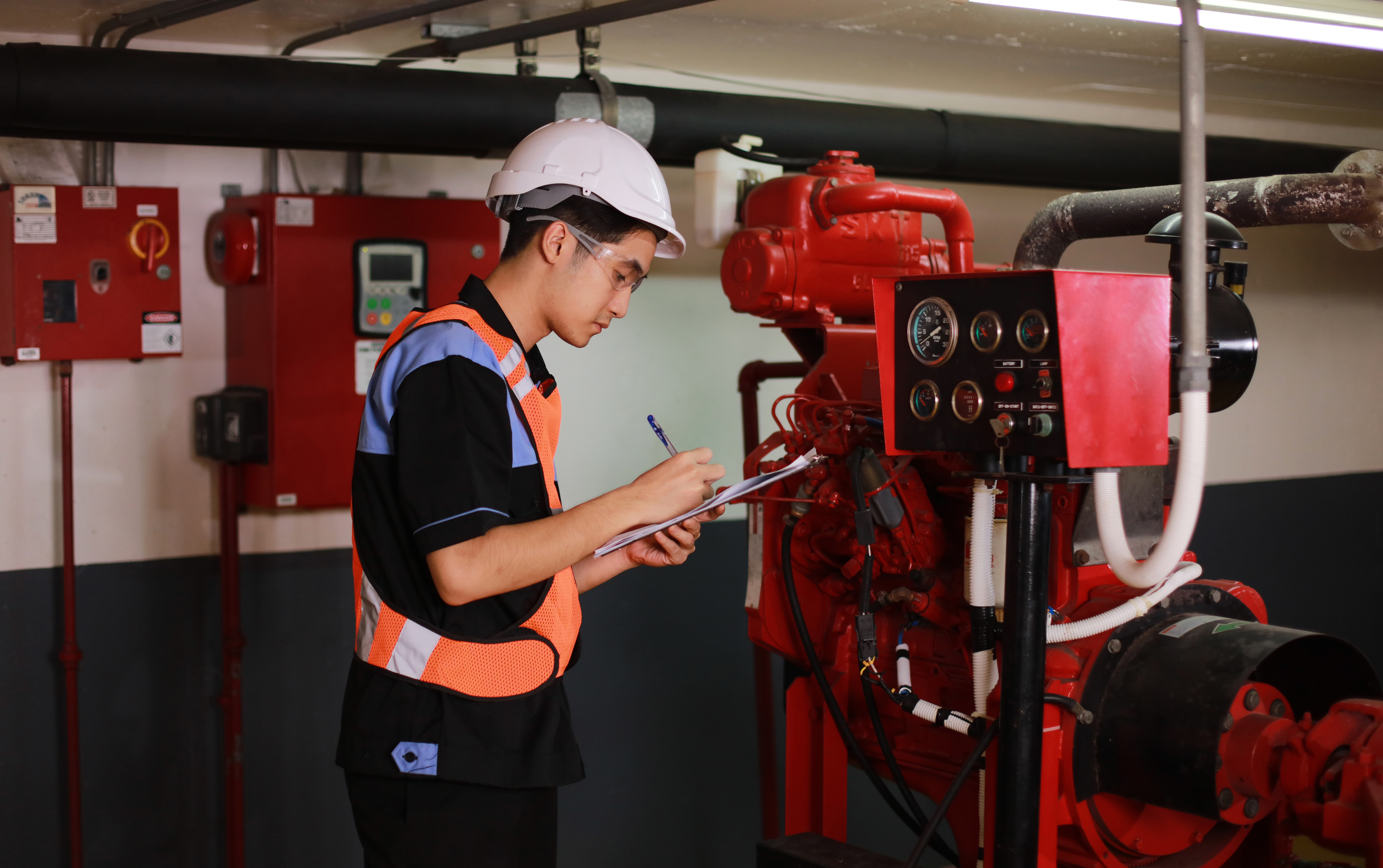 Technician inspecting industrial equipment, taking notes.