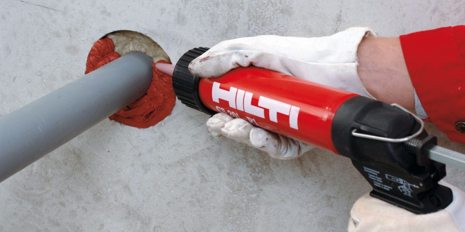 Applying sealant around pipe with tool.