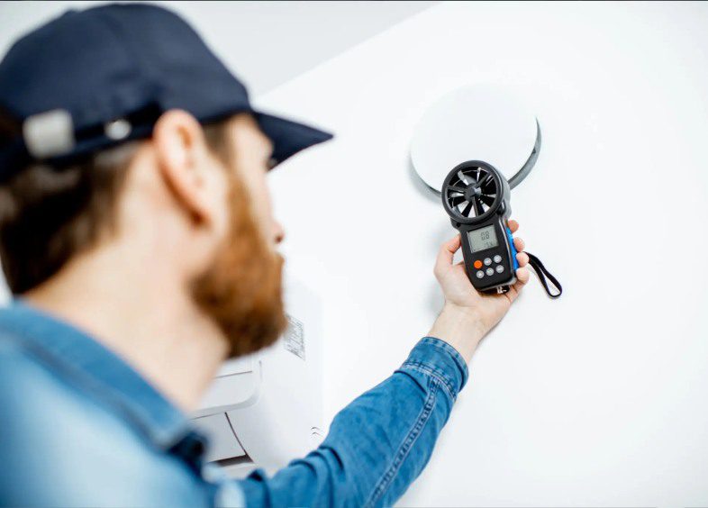 Technician measuring airflow with anemometer device.